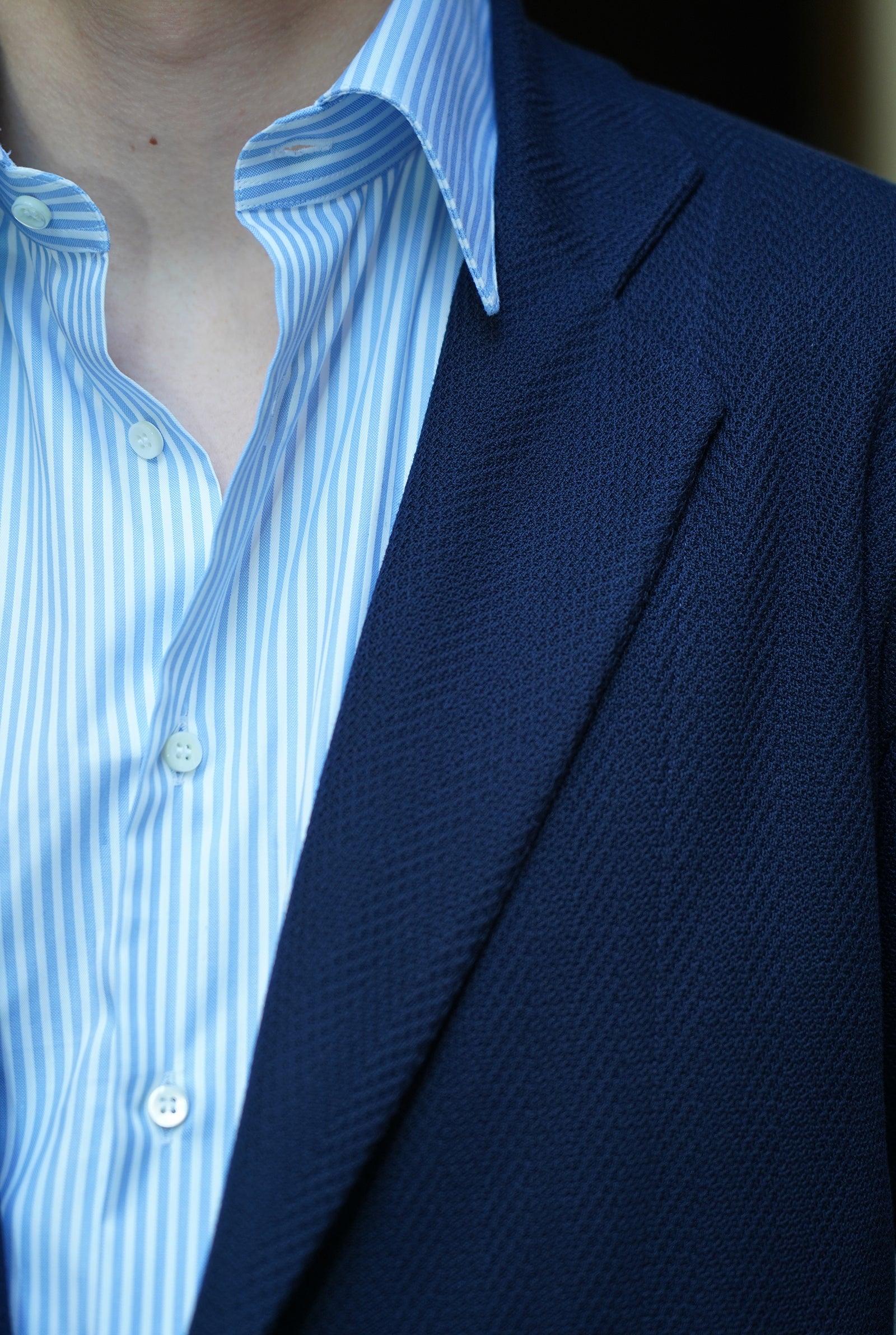 Dettaglio della giacca a quattro bottoni modello Tortona e della camicia sartoriale a righe azzurre indossati amisuraduomo sartoria  a Milano